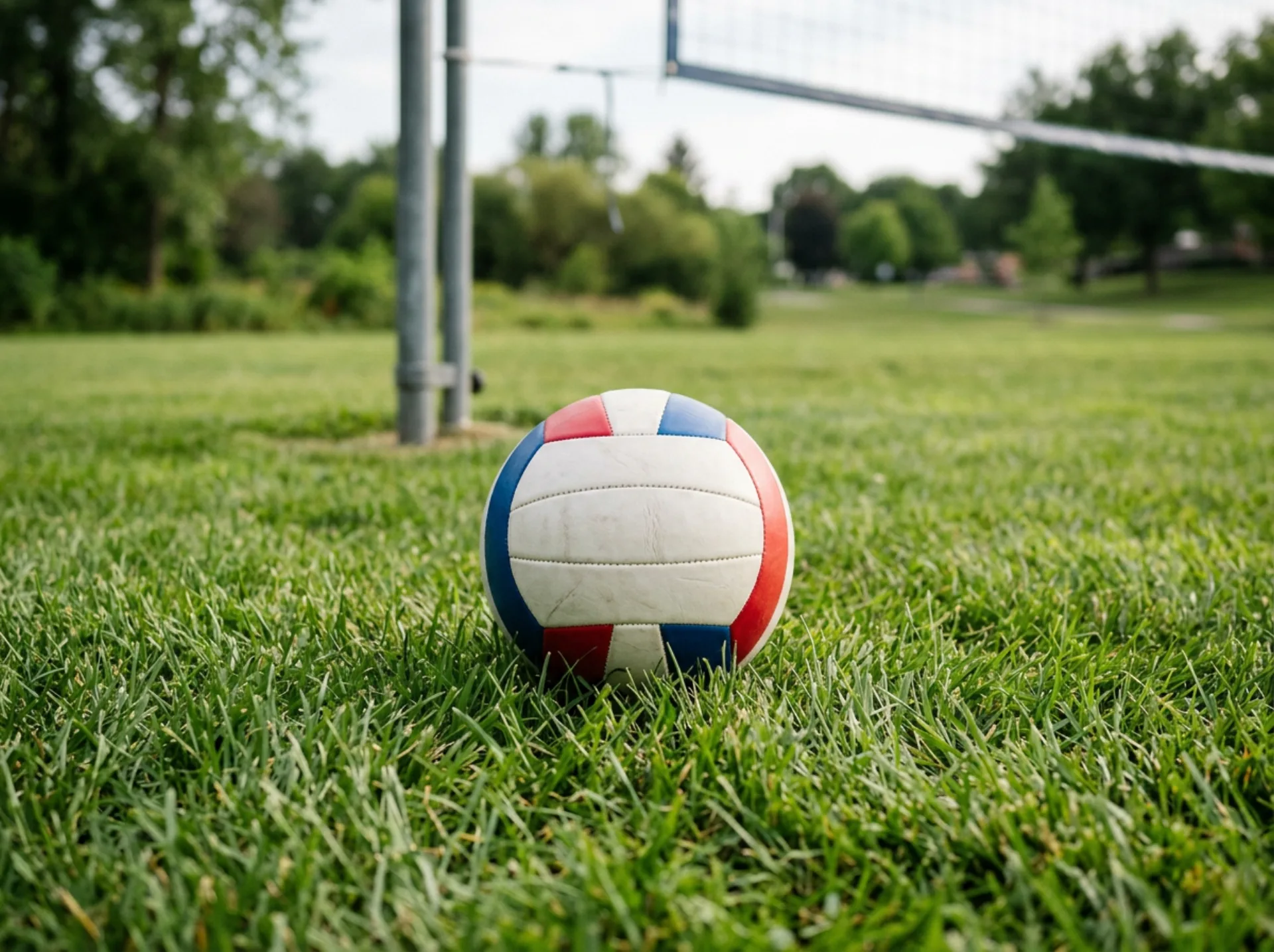 Pallone da pallavolo su un prato verde con palo della rete sfocato