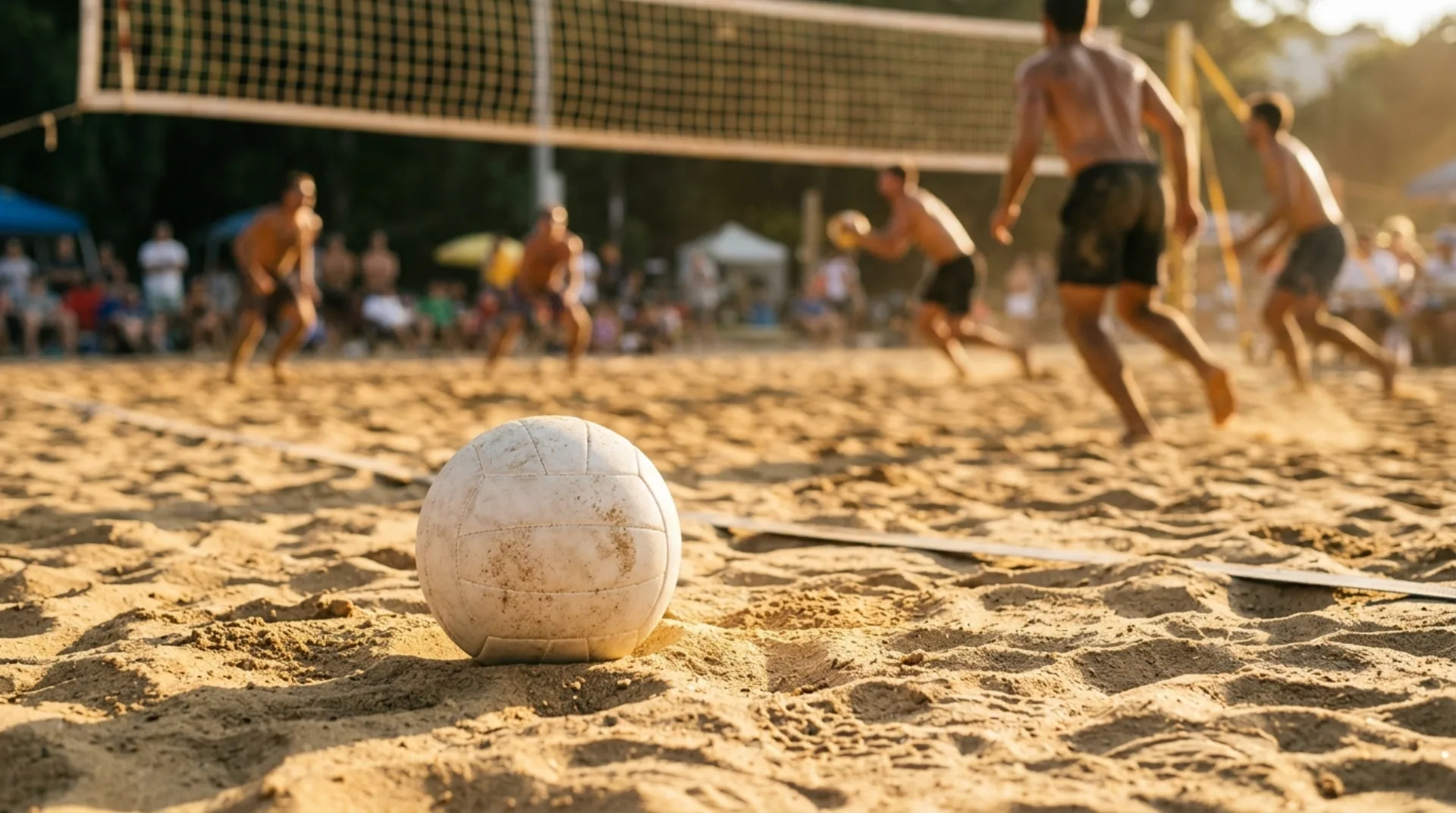Un pallone da beach volley sulla sabbia dorata di un campo da gioco con la rete sullo sfondo
