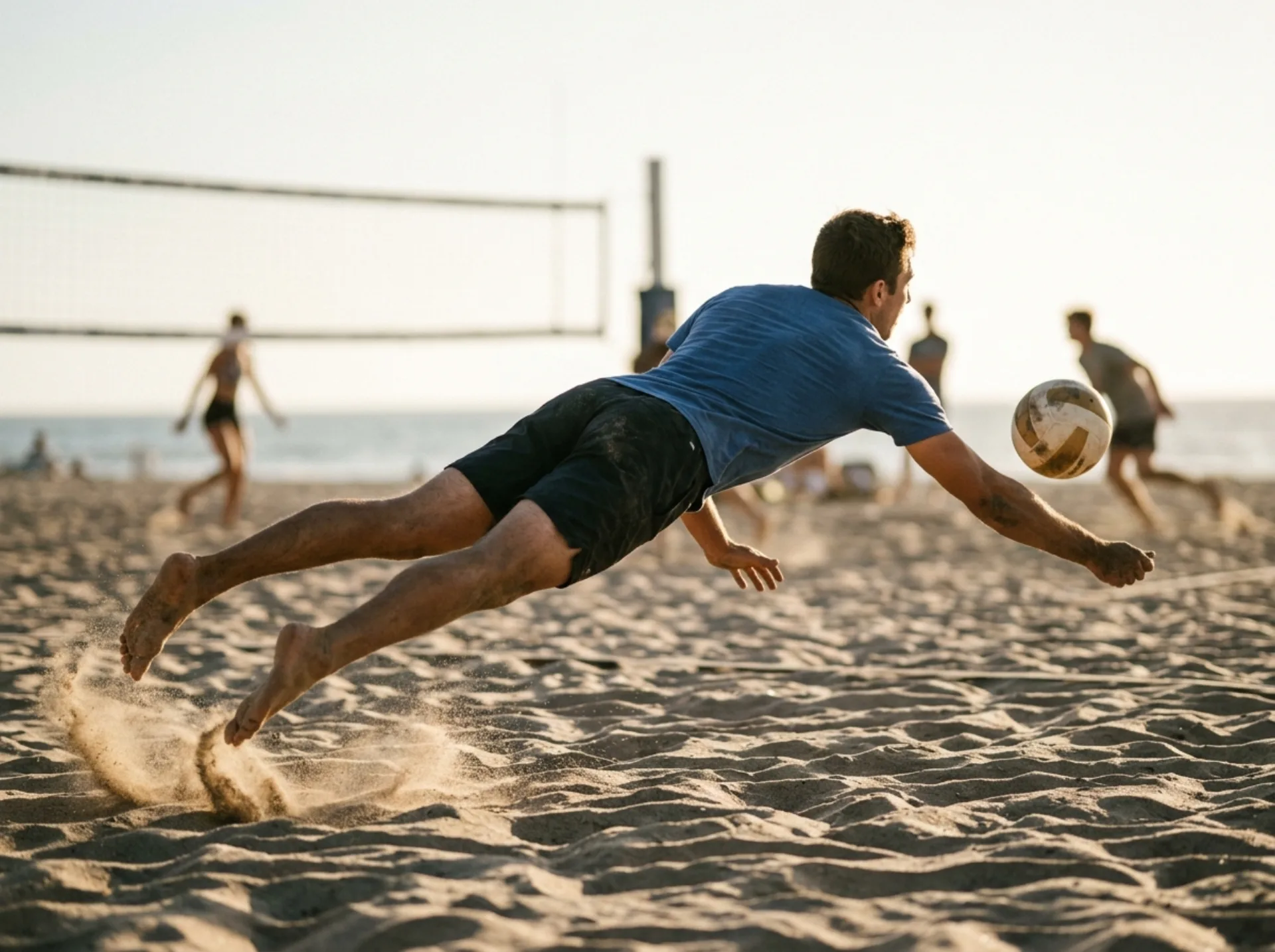Un giocatore in tuffo sulla sabbia durante una partita di beach volley.