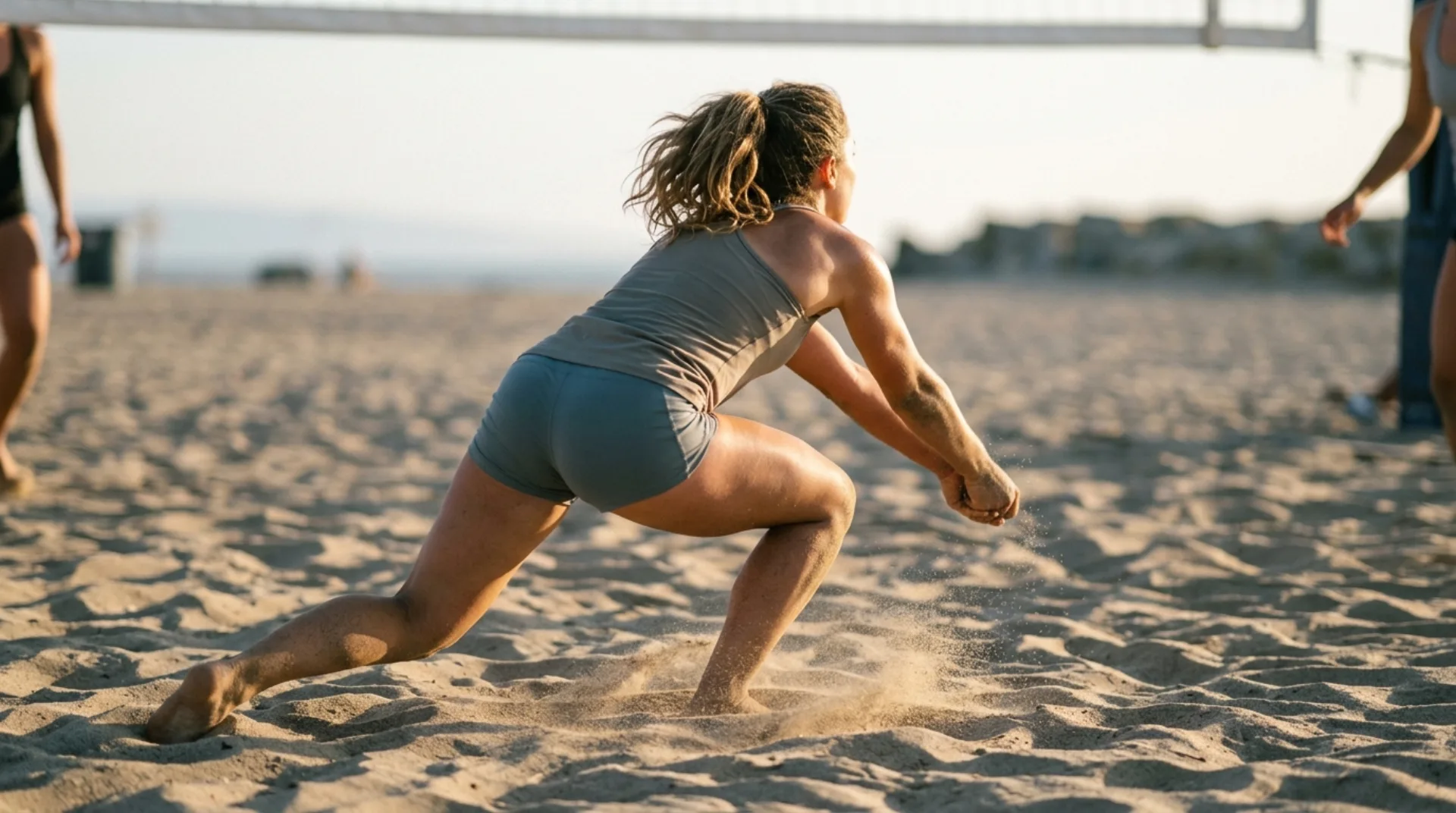 Un giocatore di beach volley che esegue un bagher basso sulla sabbia dorata al tramonto.